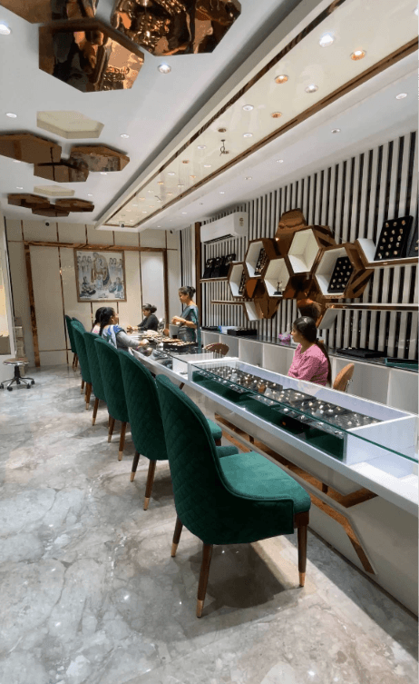Onkar Jewellers showroom interior with green velvet chairs and brass hexagon shelves